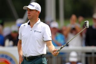 Justin Thomas holds his putter in the air