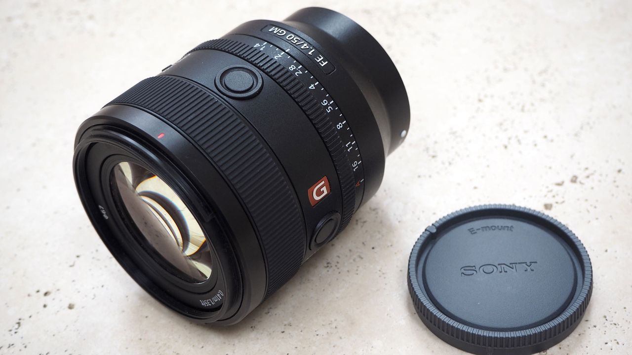The Sony 50mm f/1.4 GM lens and lens cap on a table.