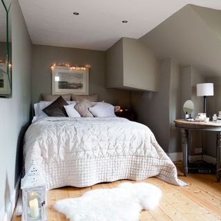 attic bedroom with grey wall and wooden floor and faux fur rug