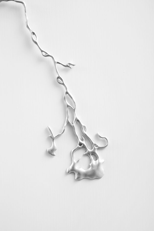 White wall, close up of the molten silver pearl sculpture