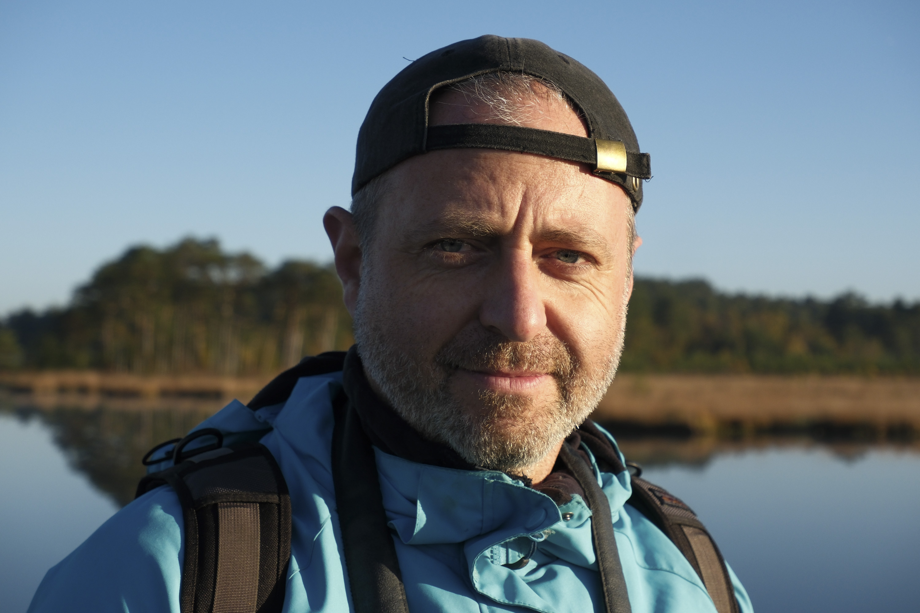 Portrait of a male at first light with a still lake backdrop, taken with the Fujifilm X-M5