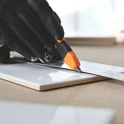 Gloved hand scribing white ceramic tile