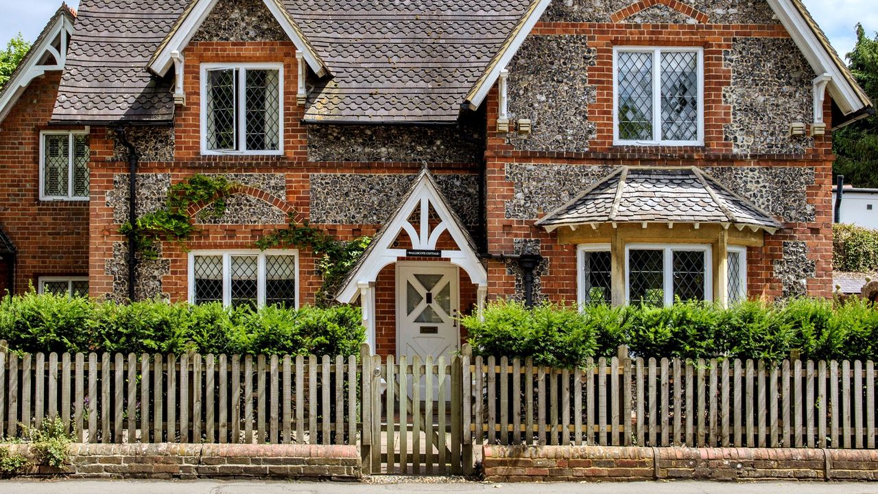 gable roof house with wooden fence adjacent to road