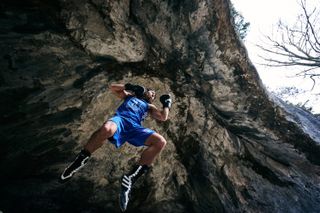 a boxer in a cave wearing clue vest, shorts, and gloves jumping, photo taken from a low angle