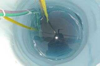 Looking down a hole in the Matanuska glacier that has just been melted by the passage of the VALKYRIE probe. The yellow cable sheaths the laser fiber.