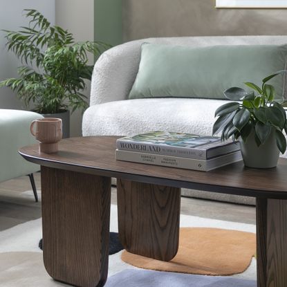 Dark wood curved coffee table with a sofa in the background 