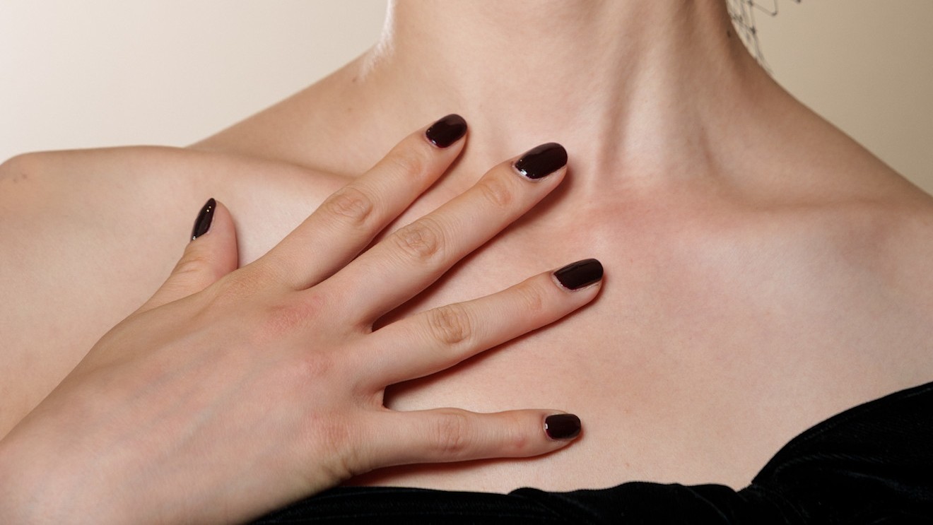 woman with black square nails against her chest