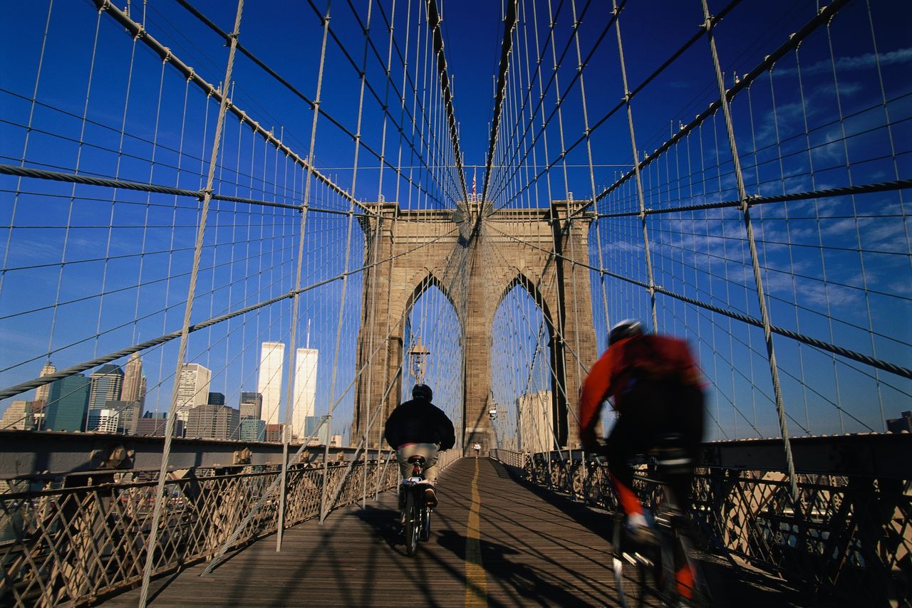 Two bikers going over a bridge
