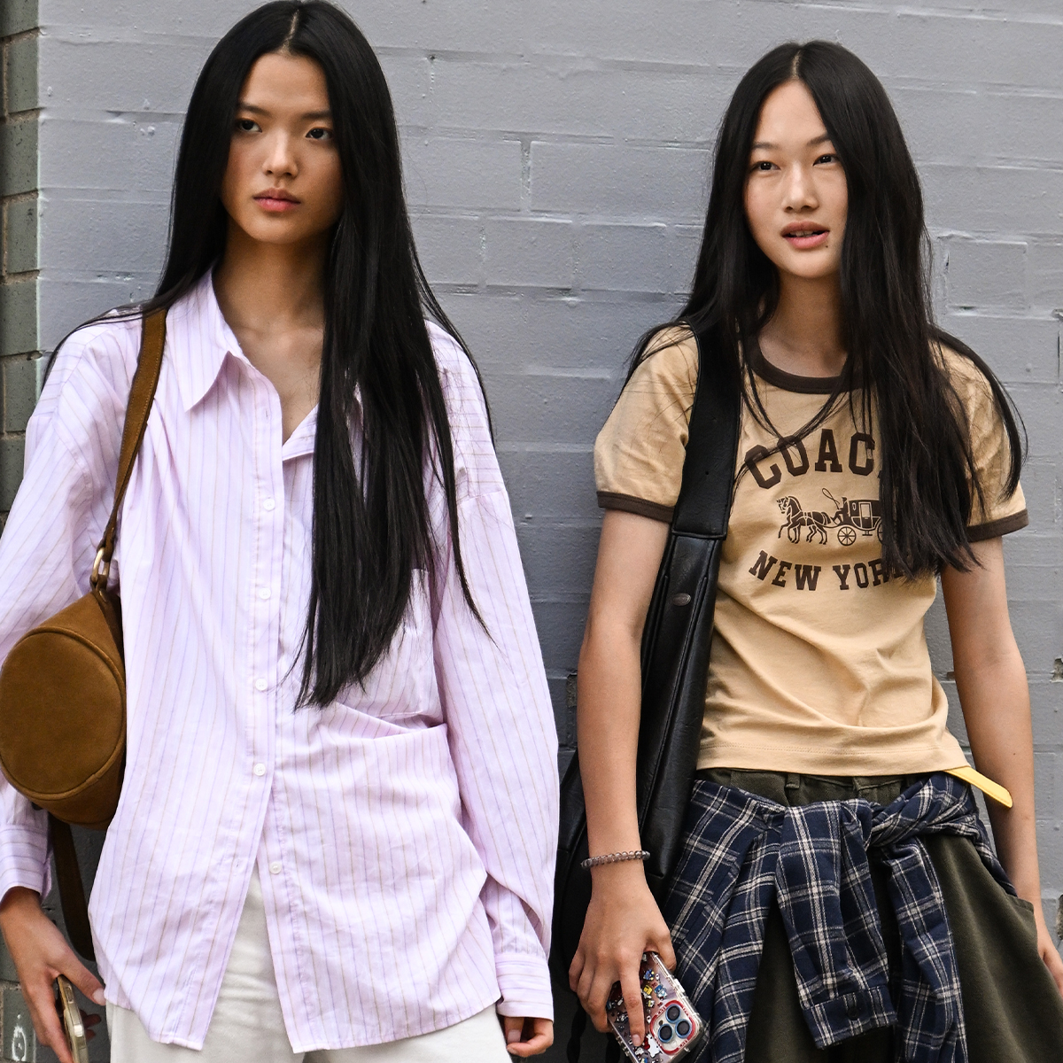 NEW YORK, NEW YORK - SEPTEMBER 15: A model is seen wearing a Coach t-shirt, gray pants, plaid shirt and black bag with a model wearing a pink button shirt, white pants and black boots with Coach bag outside the Coach show during womenswear NYFW Spring 2026 on September 15, 2025 in New York City. 