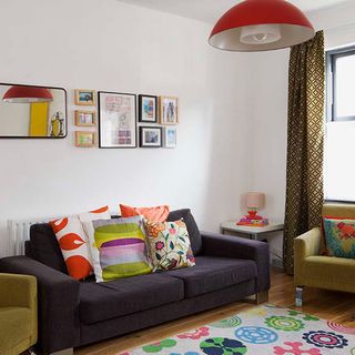 living room with frames on white wall and pillows on sofa