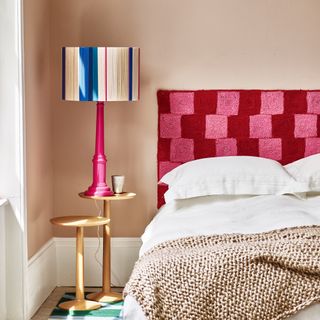 Pale pink bedroom with bright pink and red headboard and colourful table light