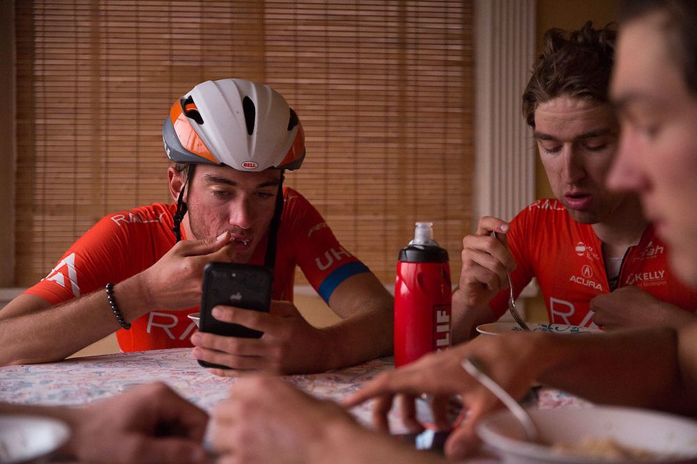 Brandon McNulty gets some food and checks his phone after a training Ride with Rally UHC