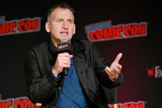 A close up fo Christopher Eccleston talking into a microphone