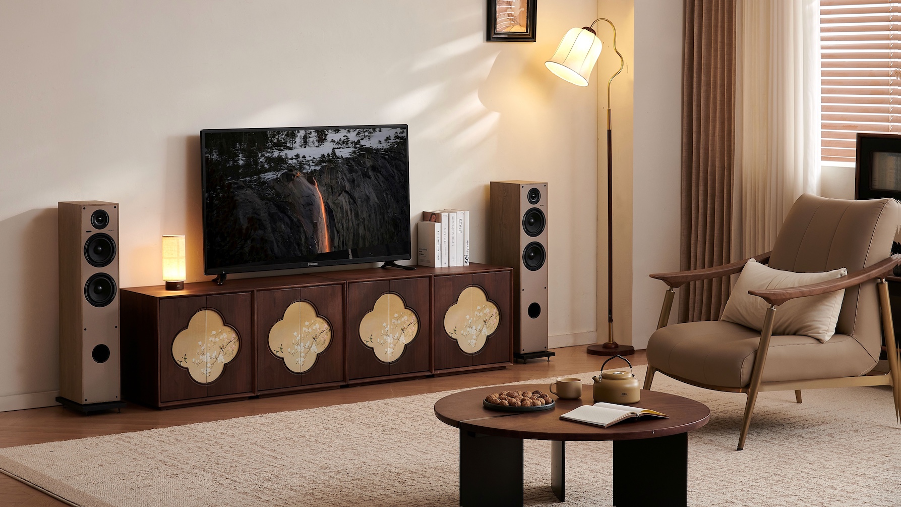 A pair of Elipson Horus 11F Active BT floorstanding speakers flanking a TV on a TV cabinet in a cosy, modern lounge.
