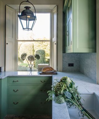 sage green small english kitchen with window shutters