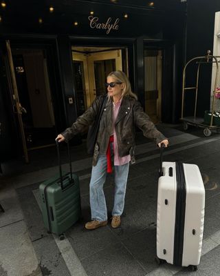 @lucywilliams02 wearing jeans and a leather jacket, holding luggage