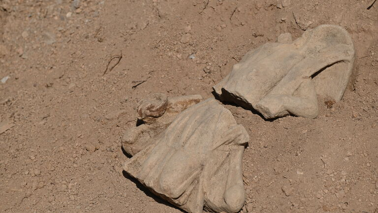 a statuette broken in two lies on the ground