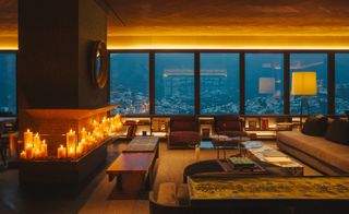 The interior of the penthouse at dusk with candles illuminating the room. Colour theme is predominantly dark brown and orange.