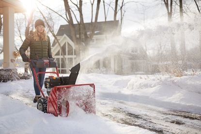 Woman showing how to use a snow blower to throw snow