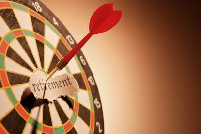 dartboard with a red dart in the bullseye and a piece of paper that says retirement