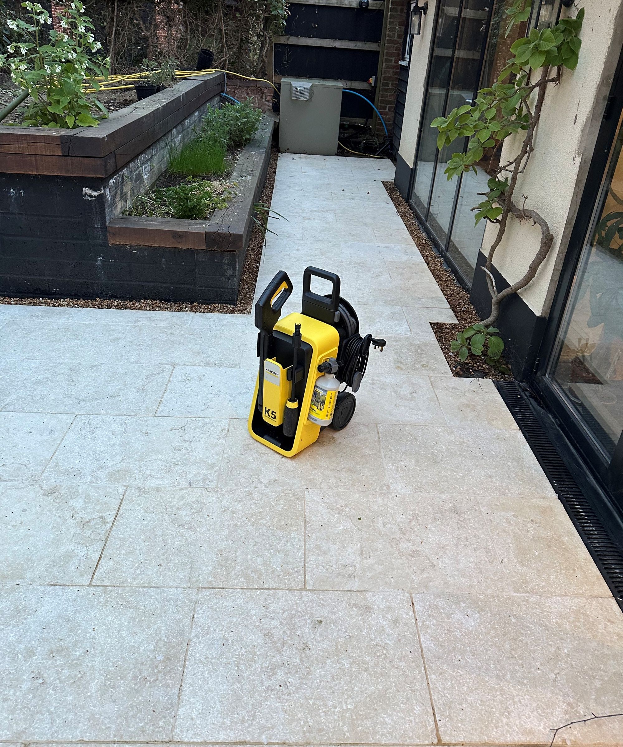 A yellow Karcher K5 Comfort Premium pressure washer on a cream limestone patio