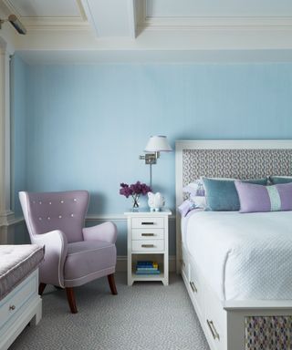 bedroom with blue walls and lavender wing back chair