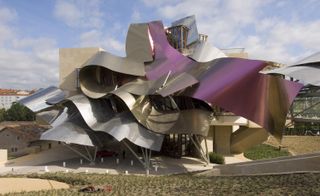 The Hotel Marques de Riscal,1999-2006, is situtated in Spain. A large structure with a roof that looks like folded paper in silver and purple.