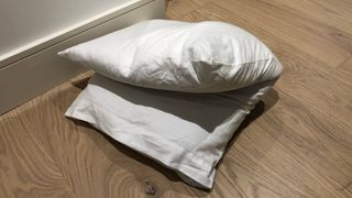 A white pillow folded in half on the floor