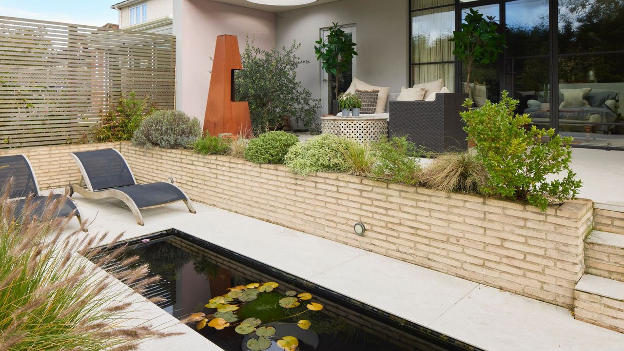 A backyard with outdoor furniture and a small pond