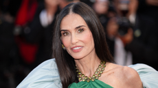 Image of Demi Moore smiling with long black straight hair and wearing a green halter-neck dress