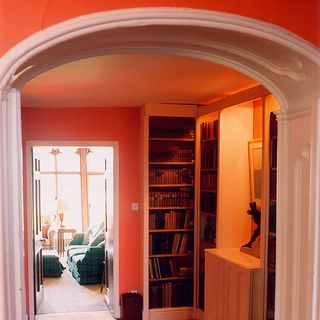 hallway with orange wall and bookcase