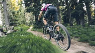 Man rapidly riding a mountain bike on a trail