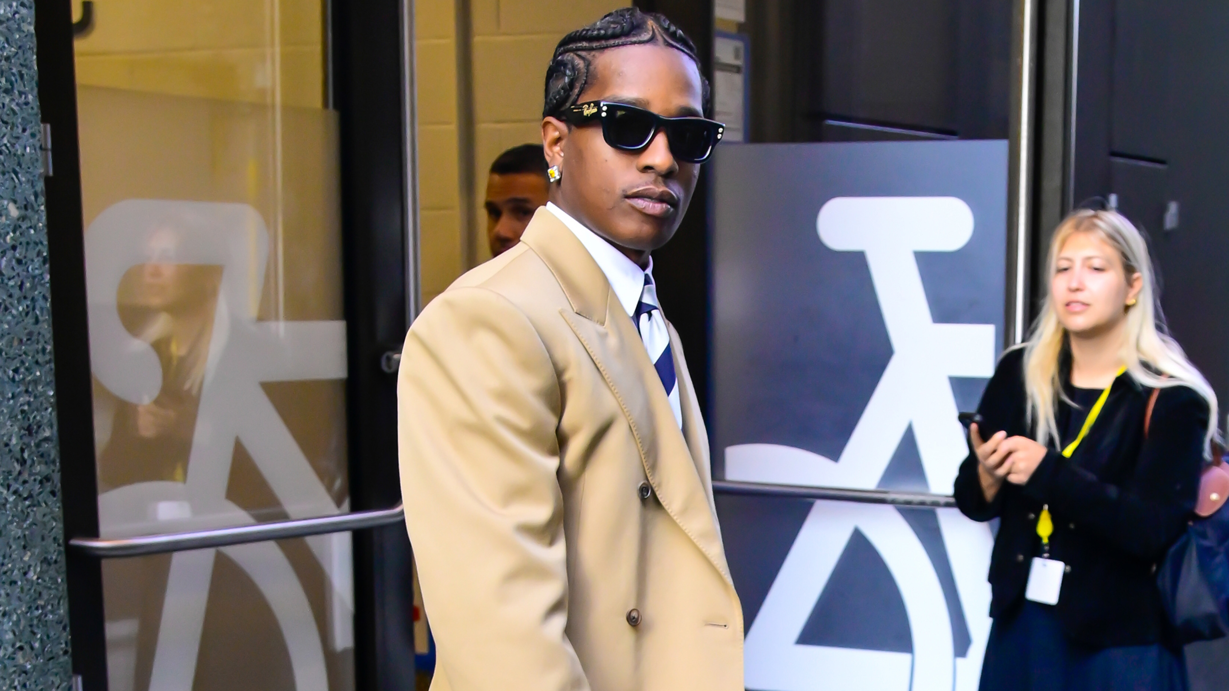 Asap Rocky wears a beige blazer, striped tie, sunglasses, and Celine&#039;s Smile luggage bag.