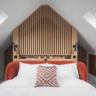 Loft bedroom with panelled walls and orange bedhead