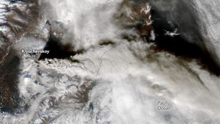 A satellite image of a large eruption plume stretching across Russia and the Pacific Ocean