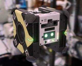One of the Astrobee robots, with its "eyes" glowing on its touch screen.