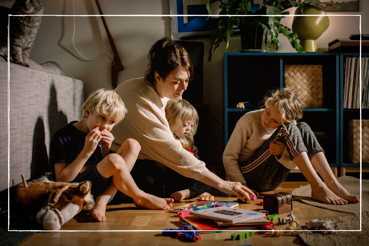 Mother sitting on floor at home playing with her three children