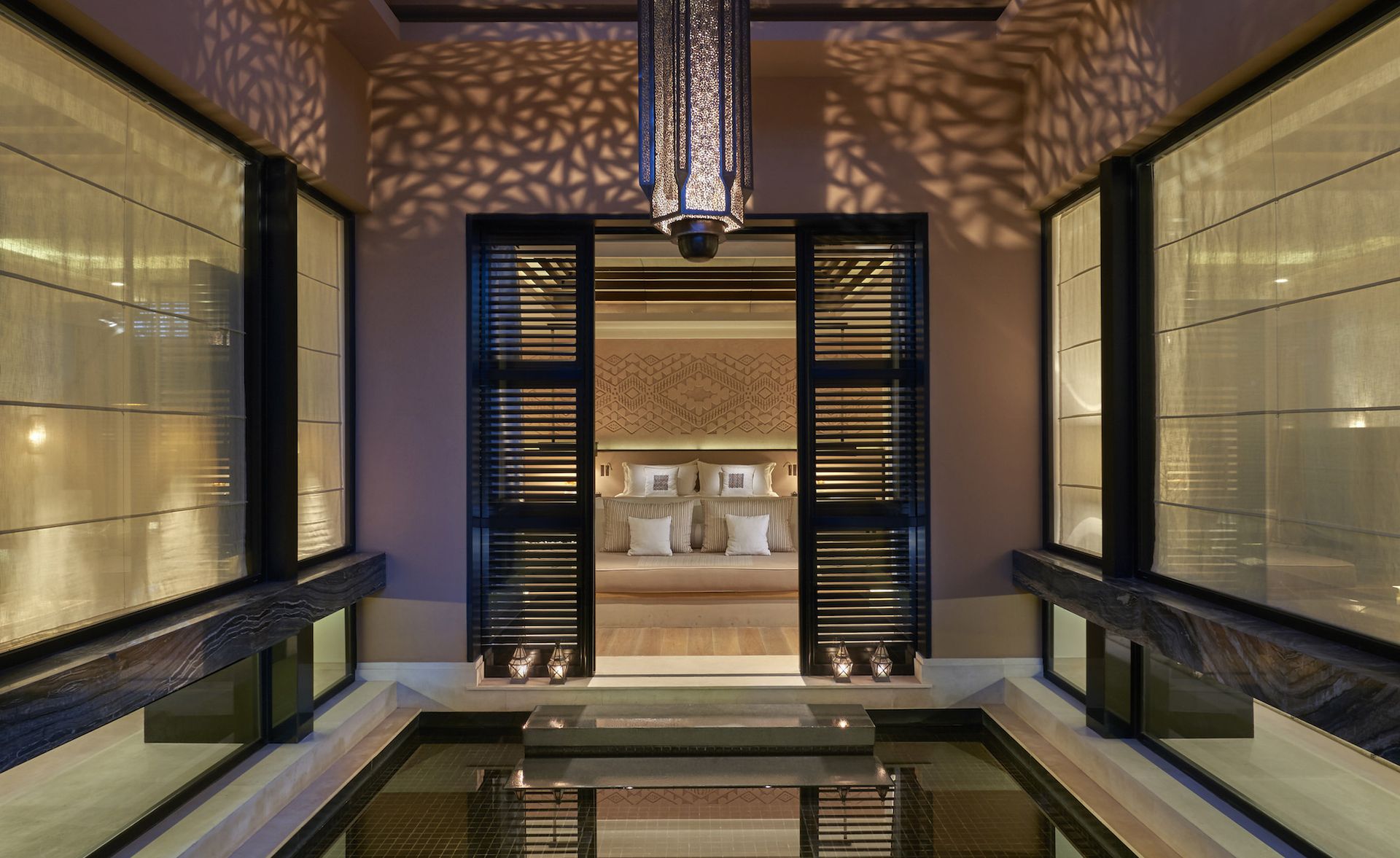 A small room with a wall to wall bath with a view through to the bedroom.