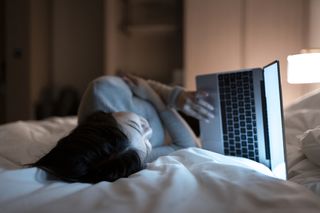 A woman watches ethical porn on her laptop in bed