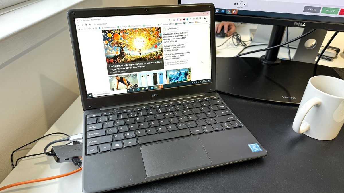 The Geobook 2E budget laptop on a desk in front of an external monitor in a brightly lit office