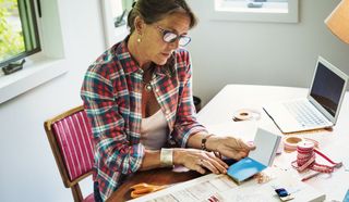 Woman looking at interior design moodboard with laptop on desk