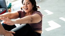 Happy woman doing sit-up with support of a trainer