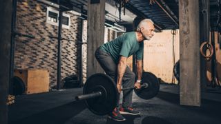 Older man doing deadlifts in gym