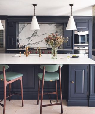 A kitchen with a light island countertop and dark blue cabinetry