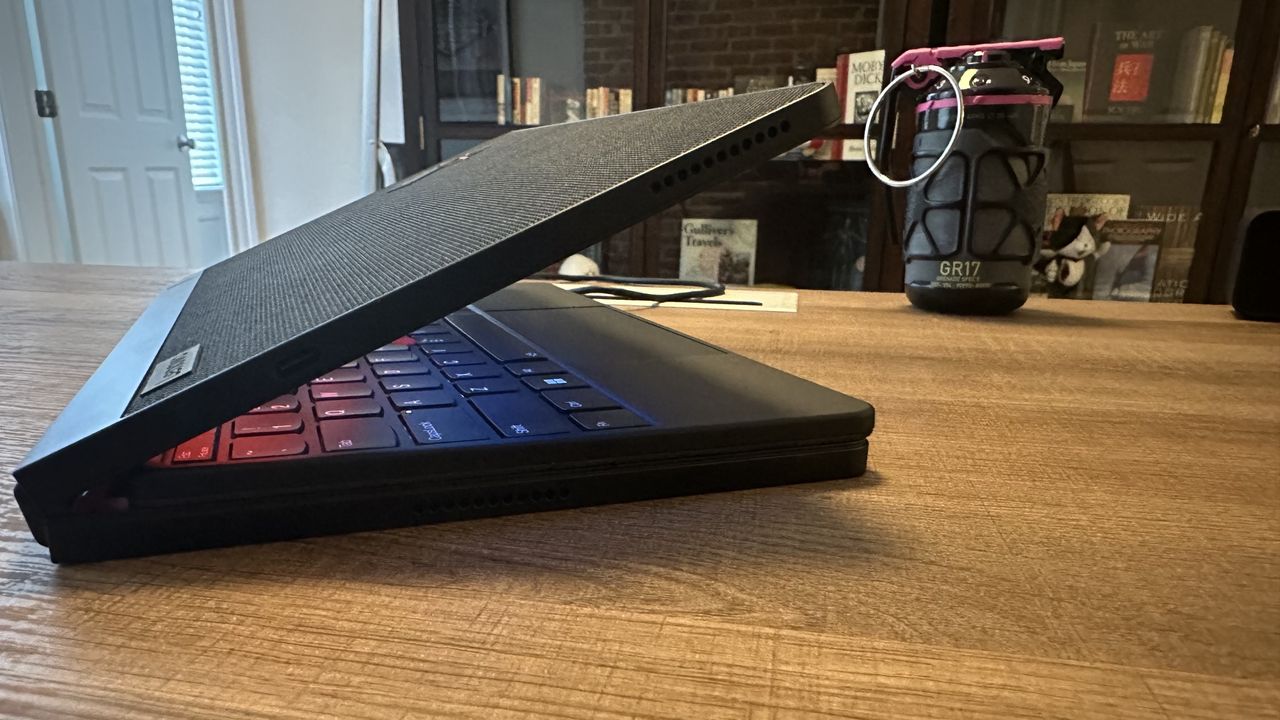 The Lenovo ThinkPad X1 Fold 16 Gen 1 with lid cracked open on a wood desk