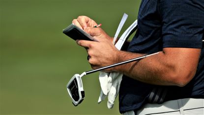 A player checks his scorecard - images for gross score in golf article