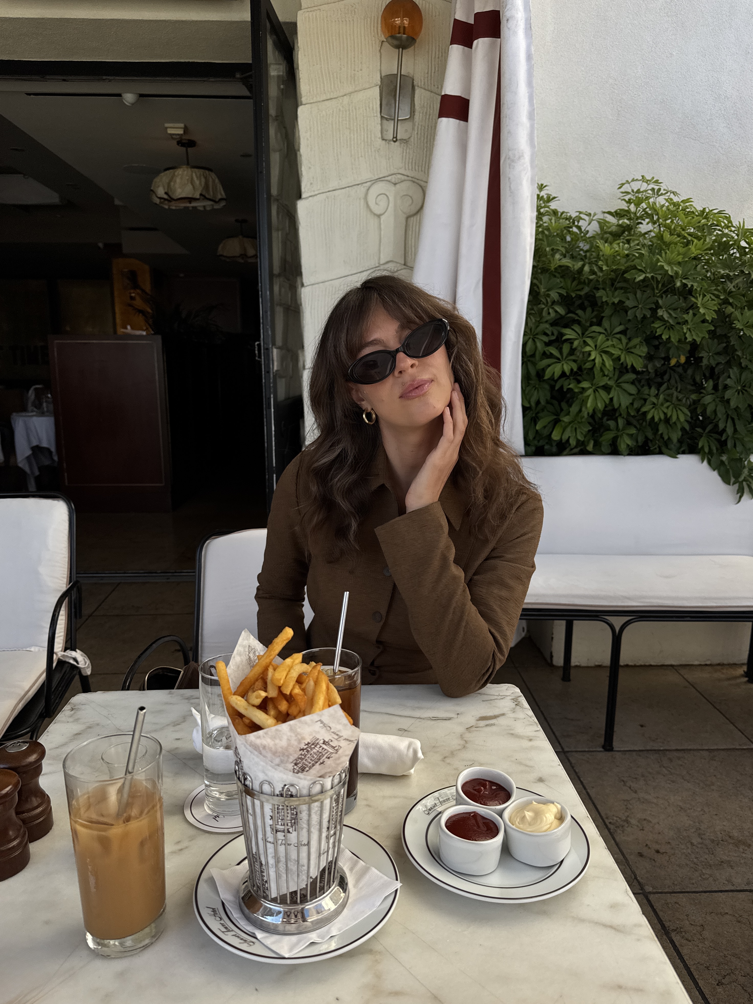 Kathryn Zahorak wearing sunglasses and brown top sitting at restaurant