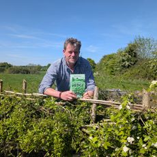 The author displaying his book while leaning on a recently laid hedge