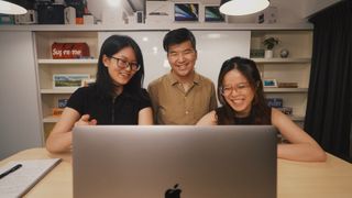 Three people looking at a laptop display