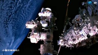 Two Shenzhou 15 astronauts work outside the nation's Tiangong space station on April 15, 2023, as seen by a camera on a space station robotic arm.